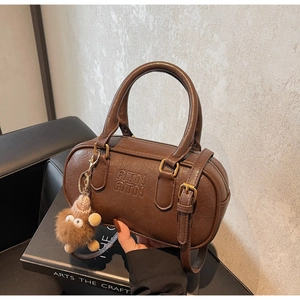 Detail of deep brown vintage Boston bag with embossed logo and fuzzy monster charm