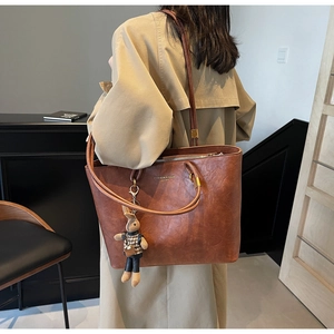 Détail du grand sac cabas marron avec charm lapin et logo doré sur cuir texturé souple