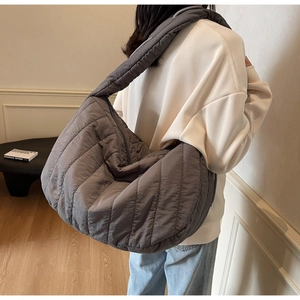 Detail of a large quilted hobo bag with horizontal padding and a wide shoulder strap