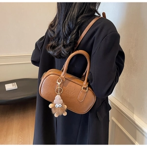 Detailed back view of a brown vintage Boston bag with plush monster charm and strap