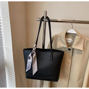 Detail of black pebbled leather tote bag with printed silk scarf on the handle