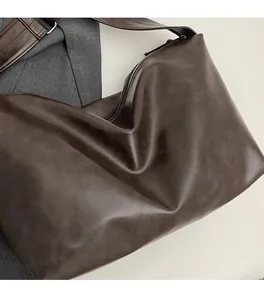 Détail du sac hobo marron foncé montrant la texture en cuir PU souple et la bandoulière