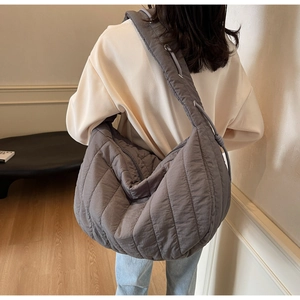 Detail of grey quilted hobo bag with adjustable drawstring strap and silver grommets