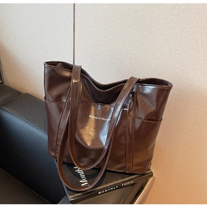 Detail of glossy brown faux leather tote bag with Believe in Yourself text print