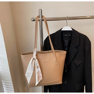 Close-up of brown pebbled leather tote bag with stylish printed scarf on a suit hanger