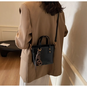 Close-up of black leather bucket bag with gold hardware worn over a khaki blazer