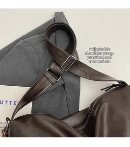 Détail de la bandoulière large réglable avec boucle argentée sur un sac cabas marron