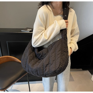 Close-up of black quilted hobo bag with textured pleats and wide shoulder strap