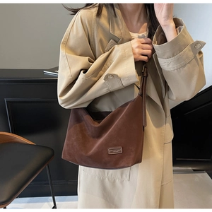 Detail of dark brown suede shoulder bag showing matte texture and minimalist patch