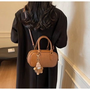Close-up of brown textured crossbody pillow bag with plush charm and embossed ATN logo