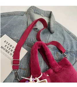 Detailed shot of plush rose pink faux fur bucket bag with adjustable strap and bead charm
