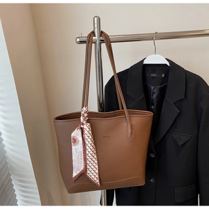 Detail of dark brown pebble leather tote bag with WWTU logo and decorative silk scarf