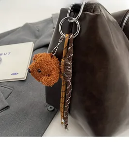 Détail d'une peluche d'ours brun et d'une corde tressée sur un sac en cuir chic