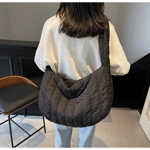 Close-up of black quilted tote bag with vertical stitching and wide shoulder strap