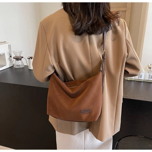 Detailed back view of a caramel brown faux suede shoulder bag worn by a model
