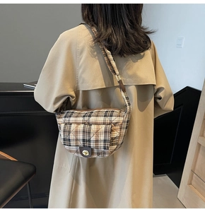 Detail of checkered quilted crossbody bag with metal twist lock on a model