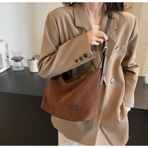 Close-up of dark brown suede hobo bag with adjustable leather strap and golden buckle