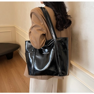 Detail view of large black patent leather tote bag with white Believe in Yourself text