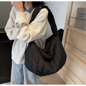 Detail of black quilted puffer tote bag showing the glossy finish and padded texture
