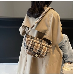 Detail of a brown plaid quilted crossbody bag with golden metal twist lock closure
