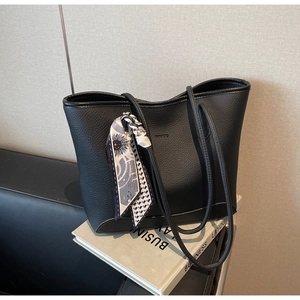 Detail of black pebbled leather tote bag with elegant geometric scarf wrapped on the handle