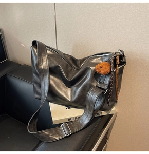 Détail d'un sac cabas en cuir PU noir mat avec large bandoulière et pendentif peluche