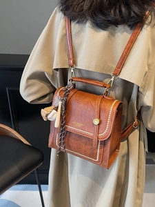 Vintage brown leather backpack for women with metal buckle and fashion baseball pendant