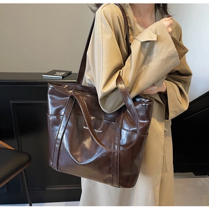 Detailed shot of large dark brown leather tote bag featuring 'Believe Yourself' text