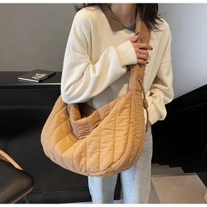 Detailed view of khaki quilted crescent tote bag showing stitched texture and wide strap