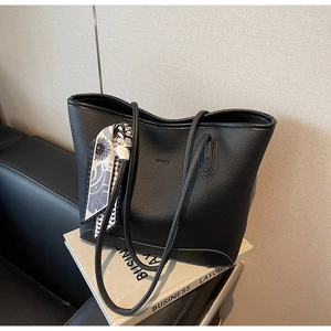 Close-up of black lychee grain leather tote bag with stylish patterned silk scarf detail