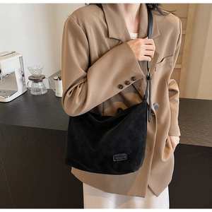Close-up of the vintage black suede shoulder bag with a minimalist logo patch detail