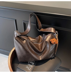 Détail du sac cabas marron foncé montrant le similicuir lisse et le charme d'ours en peluche