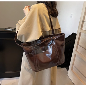 Detail of glossy chocolate brown tote bag with Believe in Yourself slogan