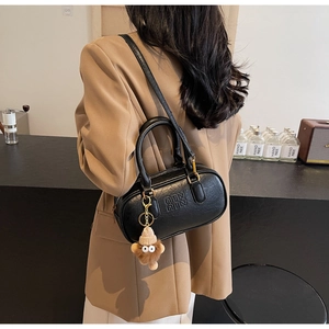 Detail of black leather Boston bag featuring ATN embossed pattern and monkey pendant