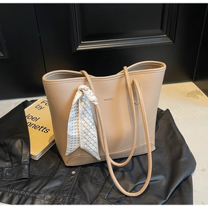 Detail of beige lychee texture tote bag with WXTU logo and decorative silk scarf