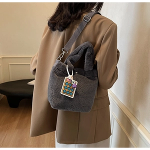 Detail of dark grey plush bucket bag with acrylic calculator charm on shoulder strap