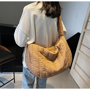 Detail view of khaki quilted puffer tote bag on shoulder with plush stripe texture