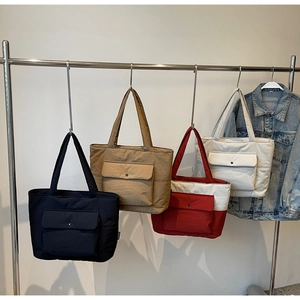 Row of large fabric tote bags in four colors showing waterproof nylon and front pockets