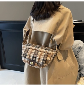Close-up of vintage plaid quilted half-moon crossbody bag with metallic twist lock on model