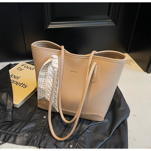 Detail of camel lychee grain tote bag with decorative silk scarf on a black leather background