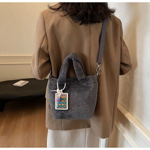 Detail of dark gray plush tote bag with plush handles and colorful calculator charm