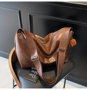 Détail du sac à bandoulière marron rétro avec large sangle et breloque ours en peluche