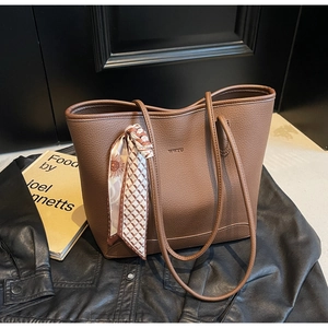 Detailed view of a brown leather tote with a decorative scarf and brand logo