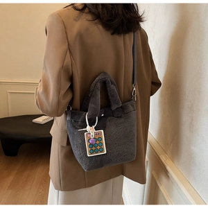 Detail of gray plush bucket bag featuring a creative calculator charm and soft furry texture