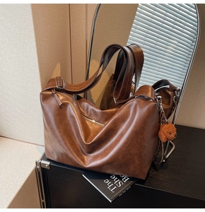 Gros plan du sac cabas en cuir marron avec fermeture éclair et pendentif chien en peluche