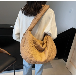 Close-up detail of oversized caramel quilted tote bag with soft padded texture and wide strap