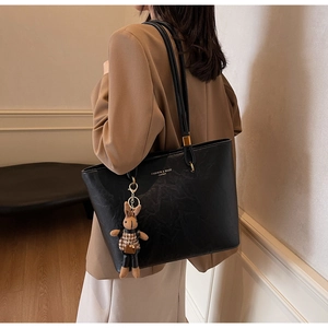 Détail du grand sac cabas noir en cuir avec pendentif lapin et logo de mode imprimé