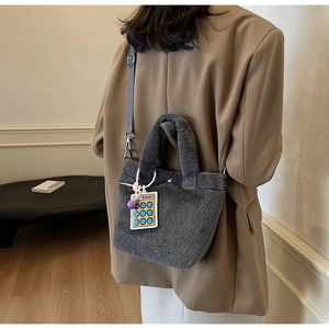 Detail of dark grey plush bucket bag with fuzzy handle and creative calculator charm