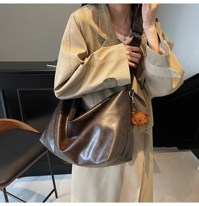 Sac fourre-tout rétro marron avec large bandoulière et breloque ours sur mannequin