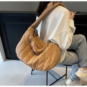 Detailed view of caramel brown quilted puffer tote bag shown on a model